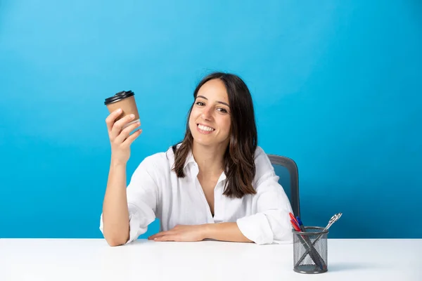 Junge Hispanische Frau Mit Einwegbecher Kaffee Sitzt Hinter Schreibtisch Isoliert — Stockfoto