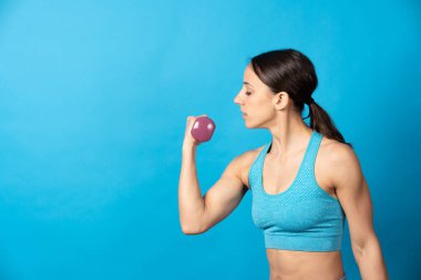 Mavi arka planda izole bir şekilde yükselen İspanyol sporcu kadının yan görünüşü.