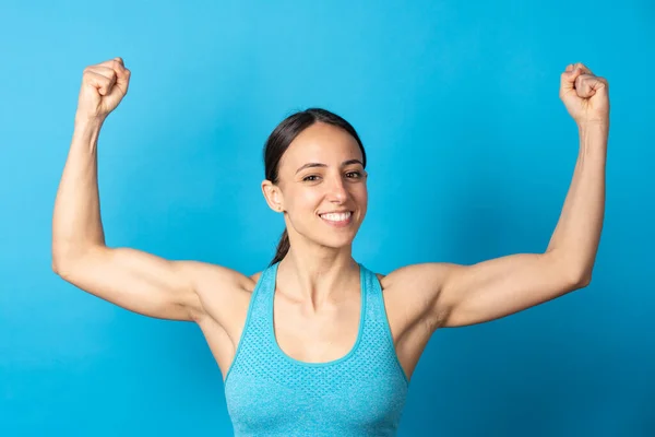 Smiling Hispanic Sportswoman Showing Biceps Looking Camera Isolated Blue Background — Photo
