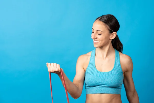 Fit Hispanic Sportswoman Using Pilates Rubber Gum Isolated Blue Background — Fotografia de Stock