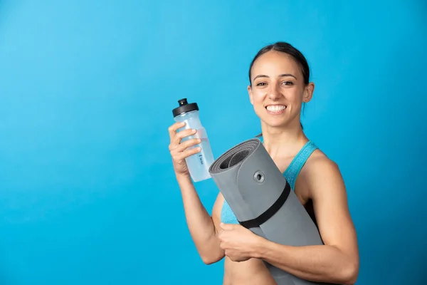 Hispanic Sportswoman Holding Yoga Mat Water Bottle Isolated Blue Background — Fotografia de Stock