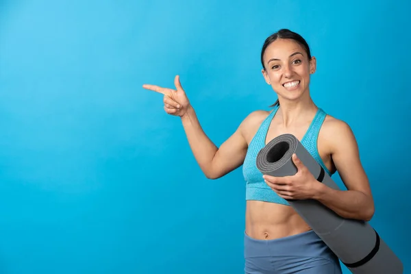 Hispanic Sportswoman Holding Pilates Mat Pointing Copy Space Isolated Blue — Foto de Stock