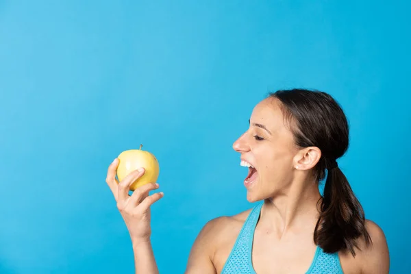 Happy Hispanic Fit Woman Looking Apple Isolated Blue Background — Zdjęcie stockowe