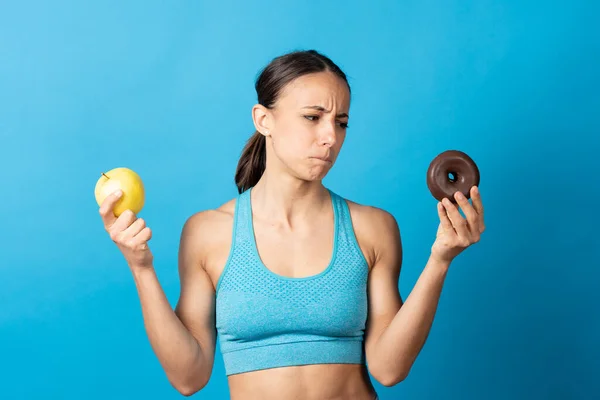 Hispanic Fit Woman Looking Donut Envy Holding Apple Isolated Blue — Stock Photo, Image