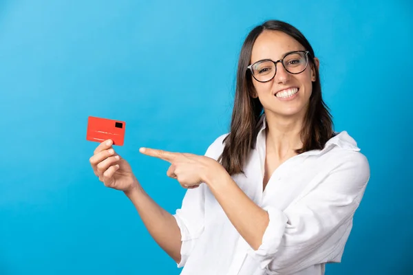 Cheerful Hispanic Woman Pointing Credit Card Looking Camera Isolated Blue — 스톡 사진