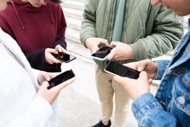 Group of friends using their phones together. Digital addiction and social distancing concept.