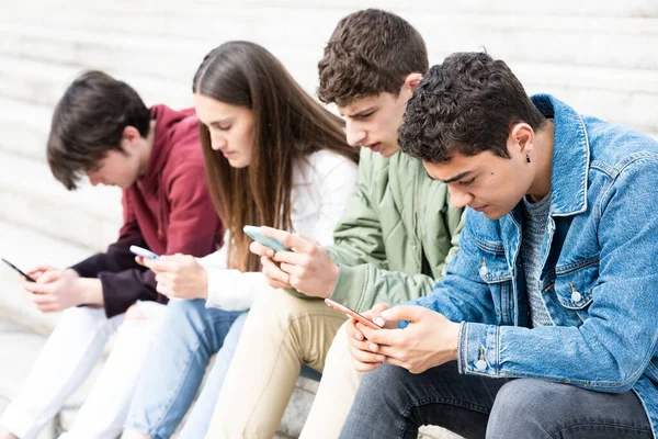 Arkadaşlarıyla telefon kullanan İspanyol ergen bir çocuk. Dijital bağımlılık ve sosyal uzaklık kavramı.