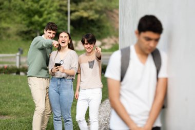 Bir grup genç İspanyol çocuğa gülüyor. Irkçılık ve zorbalık kavramı.