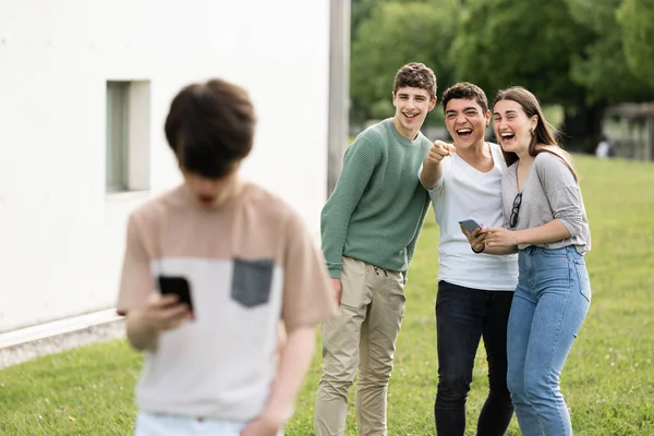 Eine Gruppe Teenager Lacht Und Zeigt Auf Den Jungen Konzept — Stockfoto