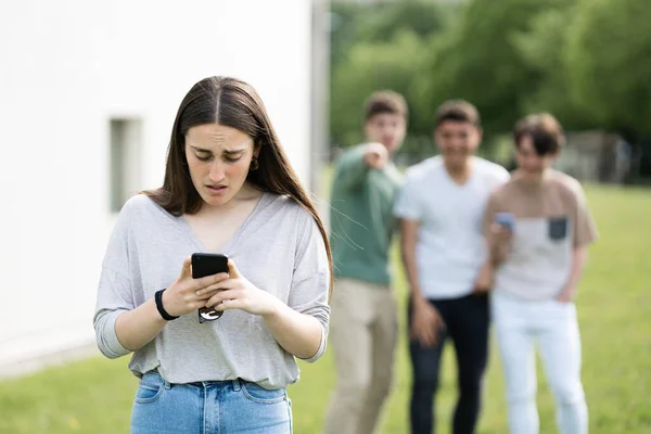 Удивлённая Девушка Подросток Смотрит Телефон Пока Друзья Смеются Над Ней — стоковое фото
