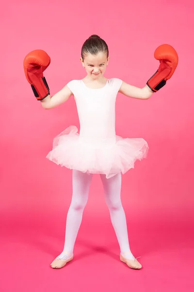 カメラを見て カラフルなピンクの背景に隔離されたボクシングの手袋を身に着けている怒っている小さなバレエダンサーの女の子 女性のステレオタイプの概念 — ストック写真