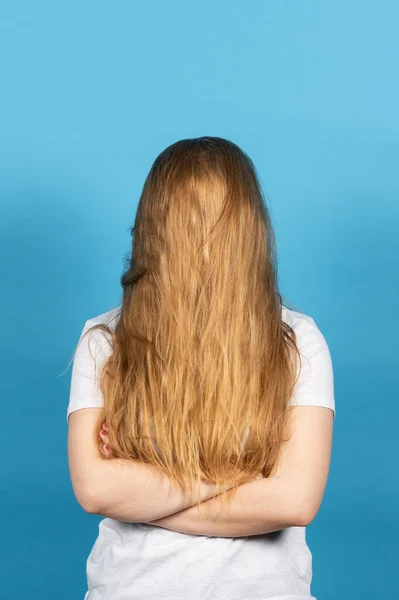 青い背景に隔離された長い髪で顔をカバーブロンドの女性 — ストック写真