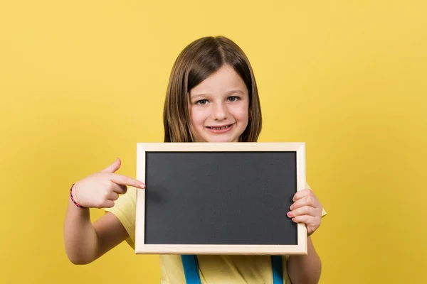 Little Girl Pointing Small Blackboard Copy Space Isolated Yellow Background — 스톡 사진