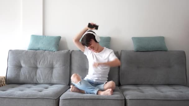 Хлопчик Підліток Танцює Слухає Музику Сидячи Дивані Вдома — стокове відео