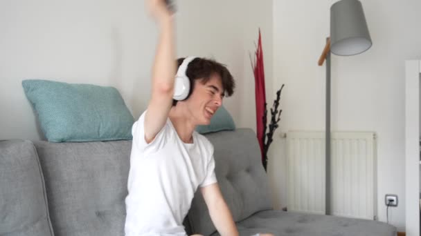 Щасливий Хлопчик Підліток Танцює Слухаючи Музику Навушниках Вдома Сидячи Дивані — стокове відео