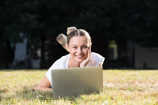 Beautiful Teenager Girl Working Laptop Looking Camera While Lying Outdoors — Zdjęcie stockowe