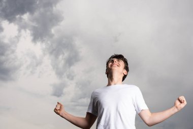 Angry teenager boy looking up at dramatic sky. Adversity, anxiety and stress concept.