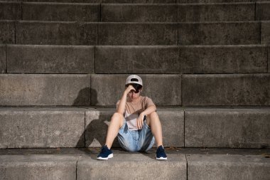 Sad pensive teenager boy sitting on staircase. Loneliness, depression and sadness concept