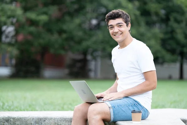 Spanyol Szabadúszó Tini Fiú Dolgozik Laptop Nézi Mosolyog Kamera Szabadban — Stock Fotó