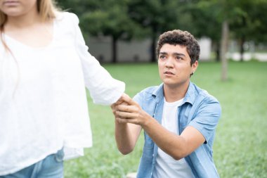 Hispanik üzgün çocuk ayrıldıktan sonra sevgilisinden ayrılmak için yalvarıyor. Ergenlik konseptinde çift ilişkisi