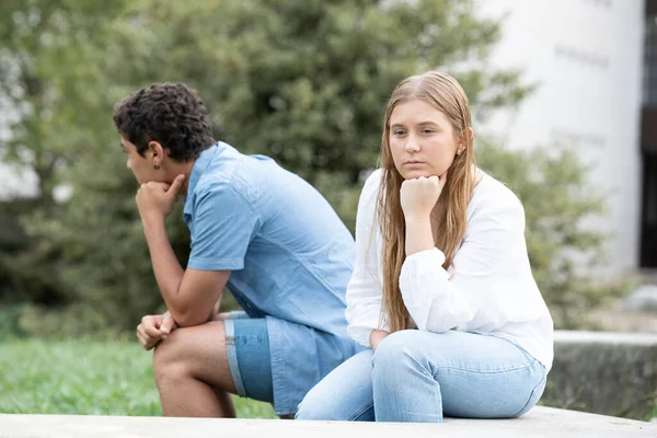 Sad couple sitting back to back thinking on relationship. Problems in adolescence concept.
