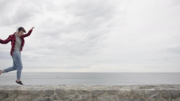 快乐的少年男孩 在多云的天气里 在海滨听音乐 在户外跳舞 — 图库视频影像