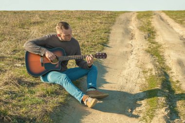 Açık havada gitar çalıyordu. Gitarlı adam.