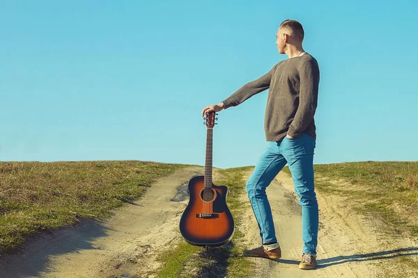 Adam elinde gitarla pistte. Gitarlı adam.