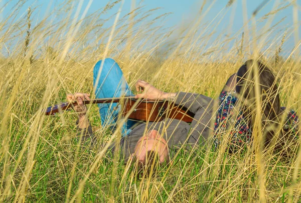 Adam ve kız çimenlerde yatıyor. Gitar çalma