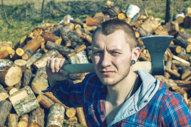 Genç bir adamın omuzlarında keskin bir balta. Omuzlarında balta olan bir adam.