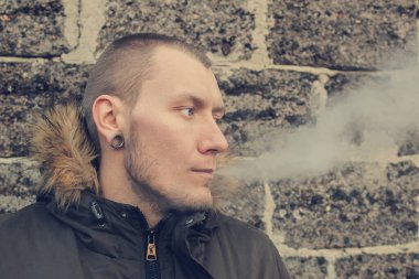 Genç bir adam çift nefes verir. Zararlı sigara alışkanlığı. Serin hava