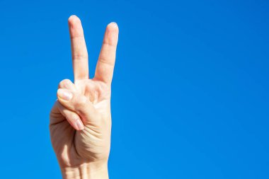 Barışın sembolü. Parmaklarını kaldır. Avuç içi mavi gökyüzünde