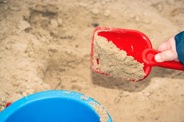 Play in the sandbox. Sand in a toy shovel. Children\'s games in the sand