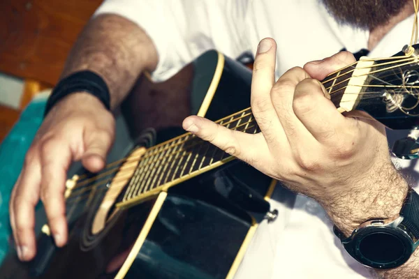 Bir müzisyenin elinde siyah gitar. Bir adam gitar çalıyor.