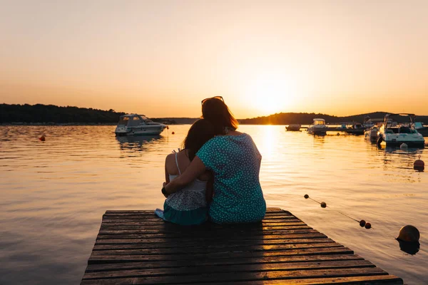 Mom Daughter Sitting Wooden Pier Hugging Each Other Admiring Setting — Stock Photo, Image