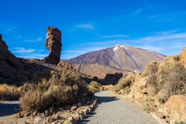 Benzersiz Roque Cinchado 'nun panoramik görüntüsü eşsiz bir kaya oluşumu ünlü Pico del Teide dağ volkanı zirvesi arka planda güneşli bir günde, Teide Ulusal Parkı, Tenerife, Kanarya Adaları, İspanya