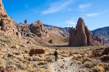 Benzersiz Roque Cinchado 'nun panoramik görüntüsü eşsiz bir kaya oluşumu ünlü Pico del Teide dağ volkanı zirvesi arka planda güneşli bir günde, Teide Ulusal Parkı, Tenerife, Kanarya Adaları, İspanya
