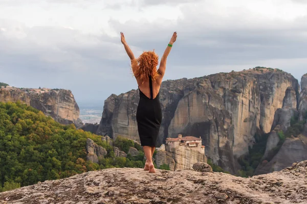 Yunanistan 'daki Meteora manastırı yakınlarındaki dağlarda doğanın tadını çıkaran siyah elbiseli genç kadın..