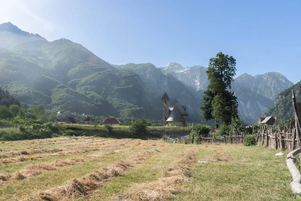 木製のフェンスを持つ道は アルバニアアルプスの山々を背景に テスバレーのカトリック教会をリードします — ストック写真