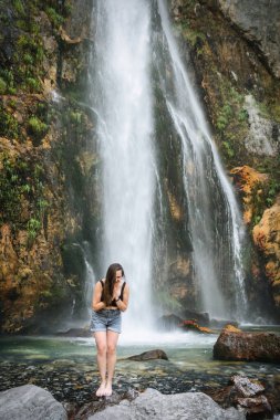 The cold, icy water of an alpine waterfall beneath Mount Goverla refreshes after a hot day. Healthy beautiful girl bathes in fast streams of a clean stream