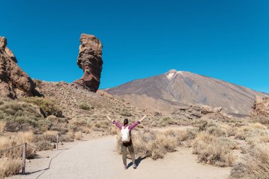 Benzersiz Roque Cinchado 'nun panoramik görüntüsü eşsiz bir kaya oluşumu ünlü Pico del Teide dağ volkanı zirvesi arka planda güneşli bir günde, Teide Ulusal Parkı, Tenerife, Kanarya Adaları, İspanya