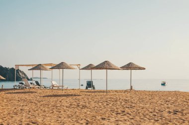 kumlu sahil üzerinde rattan ve şezlong şemsiye