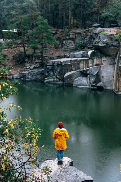 Sarı ceketli ve kahverengi şapkalı kız. Sonbahar dağlarında bir yürüyüş. Korostyshiv Kanyonu 'ndaki kayalıklarda yürüyen bir yürüyüşçü..