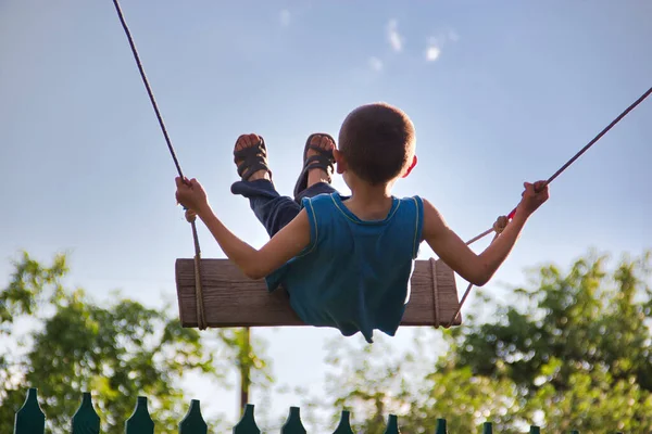 child on a rope swing against the background of the sky 2021