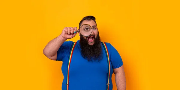 Big bearded funny man with a magnifying lens, big eye and a surprise expression