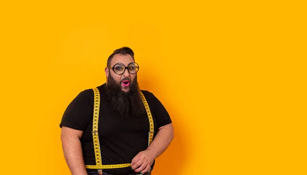 Big bearded man wearing big glasses, make-up and measure tape holders with a funny expression