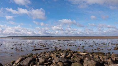 Bulutlu gökyüzü ve çakıl taşı kıyıda
