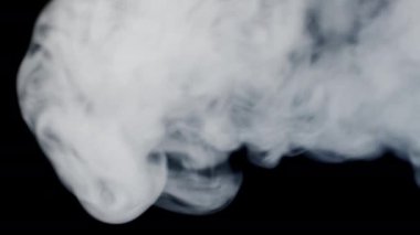 Vape smoke. Thick gray cigarette smoke blows out from the left into the frame on black background. Thick smog video in 4k resolution