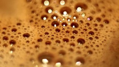Bubbles with foam with bokeh effect on surface of hot cocoa rotate in circle in cup. close-up high angle view.