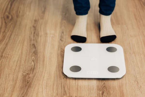 Menina mede peso em escalas inteligentes. Dispositivo eletrônico moderno. — Fotografia de Stock